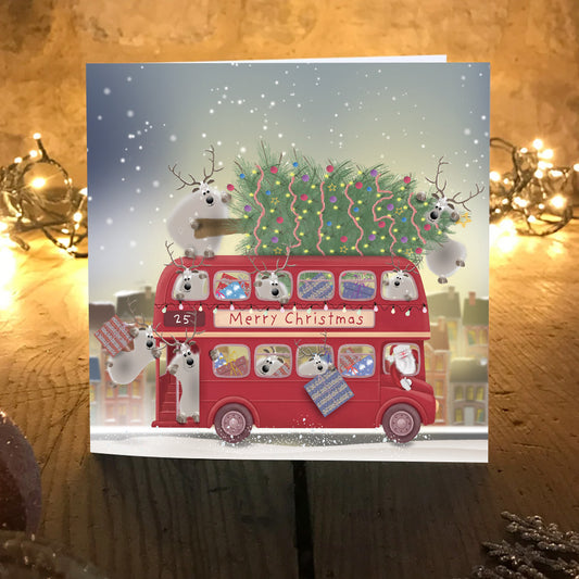 The Last Bus Christmas card displayed on a table beside glowing fairy lights