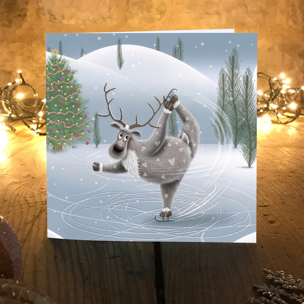 Oh Dear! spinning reindeer Christmas card displayed on a table with warm glowing fairy lights.