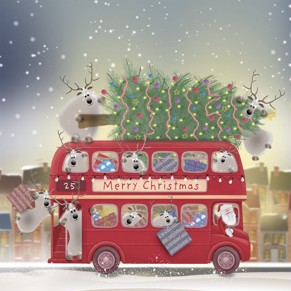 Santa and reindeer aboard a red double-decker bus carrying presents and a decorated Christmas tree through the snow