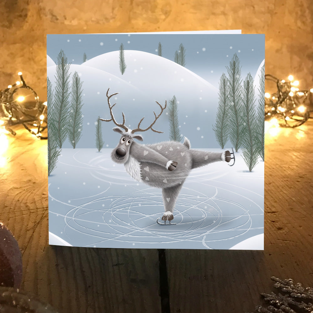 Tail Spin reindeer ice skating Christmas card displayed on a table with warm glowing fairy lights.